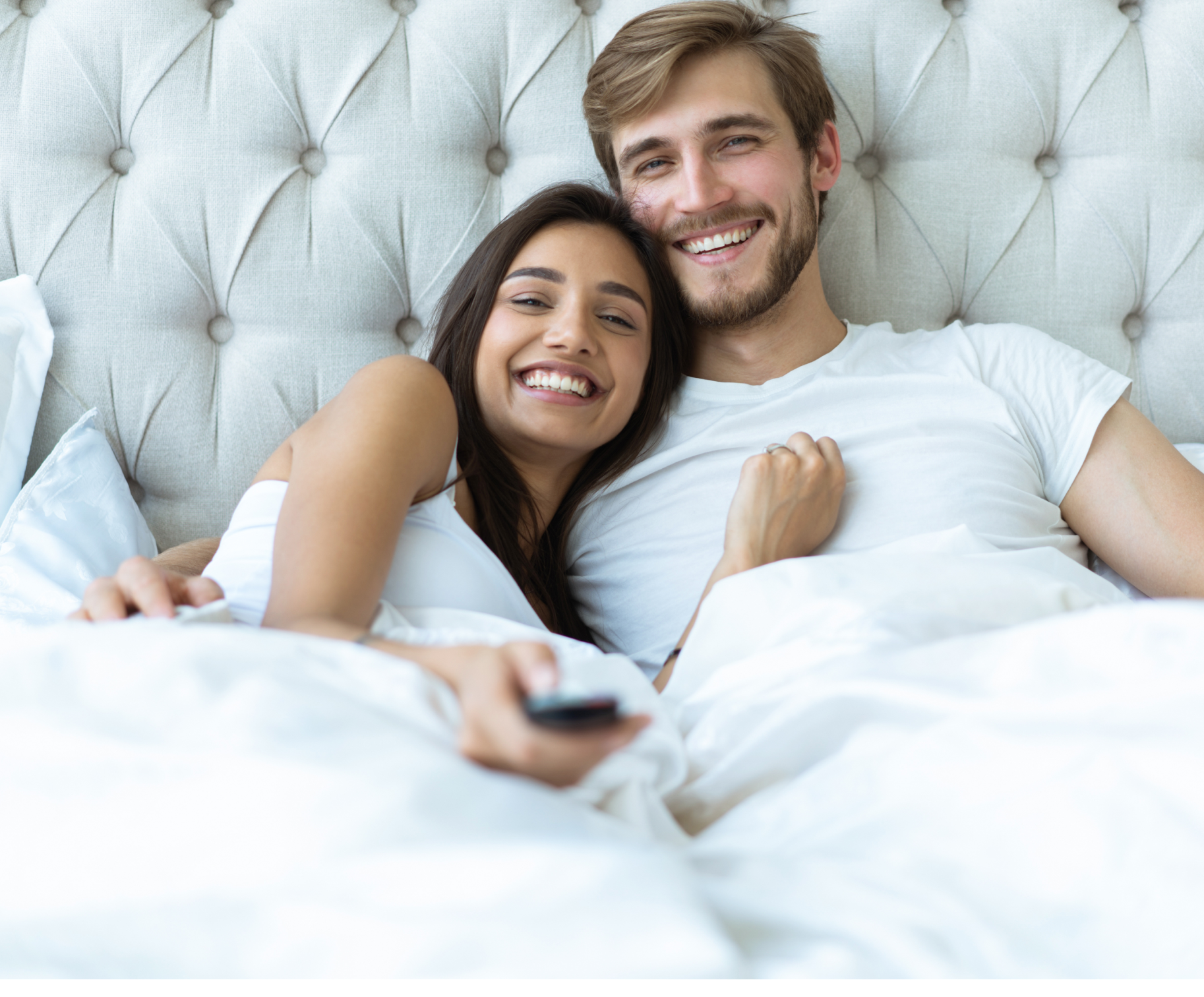 Deux personnes dans le lit entrain de profiter de la télévision.